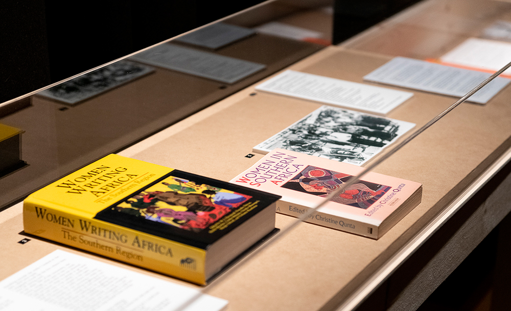 Detail of a vitrine with books, text and photograph inside. The books are titled Women Writing Africa: The Southern Region and Women in Southern Africa.